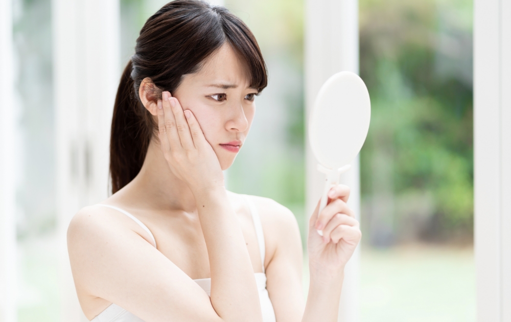 鏡を見て眉毛の状態を気にする女性